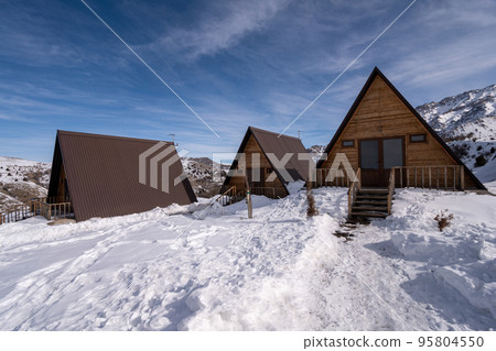 The wooden cottages surrounded by snow. A recreation area in the mountains The wooden cottages surrounded by snow. A recreation area in the mountains 95804550