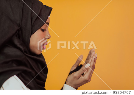 African muslim woman wearing hijab and traditional muslim clothes posing in front of yellow background 95804707