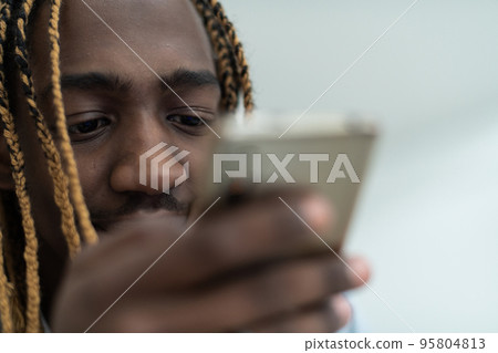 Afro guy using a smartphone and browses social media Afro guy using a smartphone and browses social media 95804813