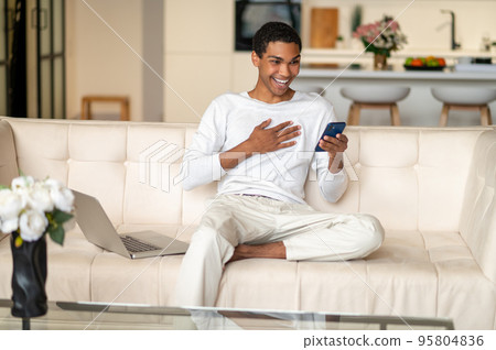 Young black man with a smartphone in hands looking happy 95804836