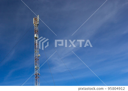 Telecommunication tower for mobile phone with antennas over a blue sky. Distribution function of contract mobile phones Telecommunication tower for mobile phone with antennas over a blue sky. Distribution function of contract mobile phones 95804912