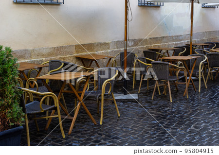 Empty wet wooden table and chairs on terrace of outdoor cafeteria during rain. Street city life in rain 95804915