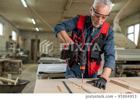 Craft person drlling wood in the workshop Craft person drlling wood in the workshop 95804953