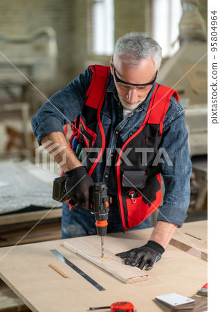 Craft person drlling wood in the workshop 95804964