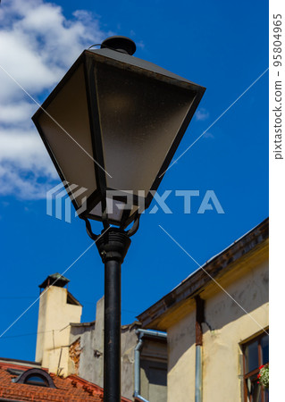 Old-fashioned street wall lamp made of black metal. Gray facade of an old house. Lviv, Ukraine Old-fashioned street wall lamp made of black metal. Gray facade of an old house. Lviv, Ukraine 95804965