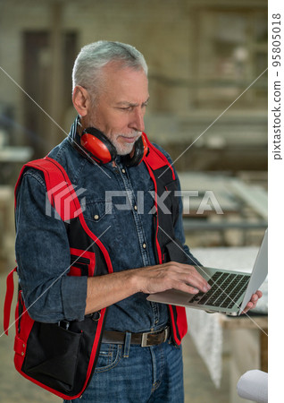 Craft person in reflective vest searching for information on internet 95805018