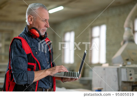 Craft person in reflective vest searching for information on internet 95805019