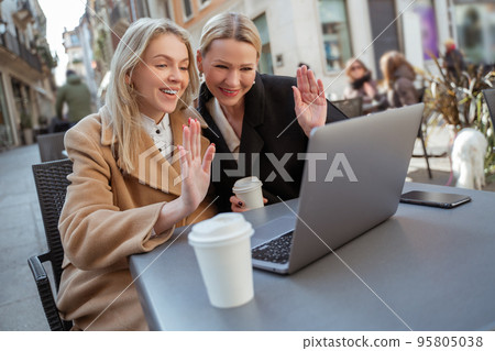 Two smiling women participating in avieo call and looking contented Two smiling women participating in avieo call and looking contented 95805038