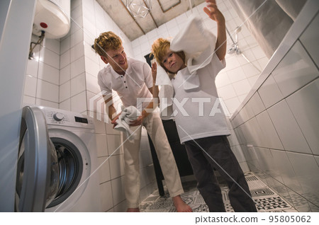 Dad and son gathering the clothes for washing in the bathroom Dad and son gathering the clothes for washing in the bathroom 95805062