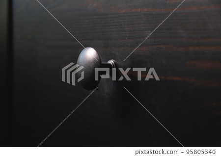 Close-up of a black wooden cabinet with round black metal handles 95805340
