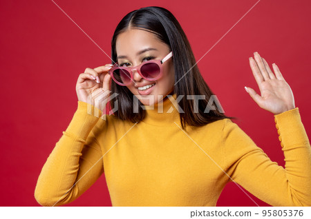 Joyful brunette posing for the camera against the red background 95805376