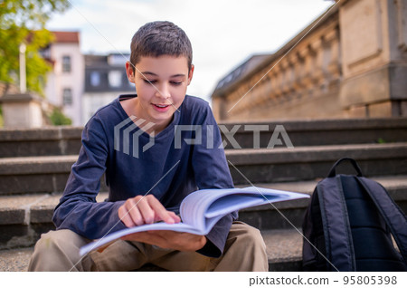 Teenage boy engrossed in reading a book 95805398