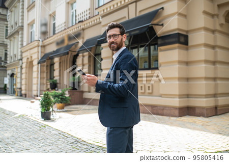 Man in elegant suit with a phone in hands in the street 95805416