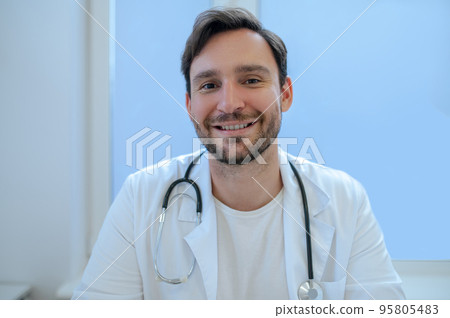 Young doctor with a happy smile sitting in his office 95805483