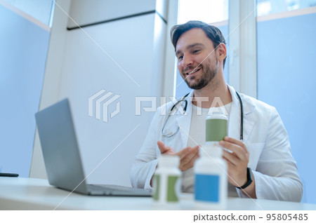 Physician prescribing vitamins to his patient online 95805485