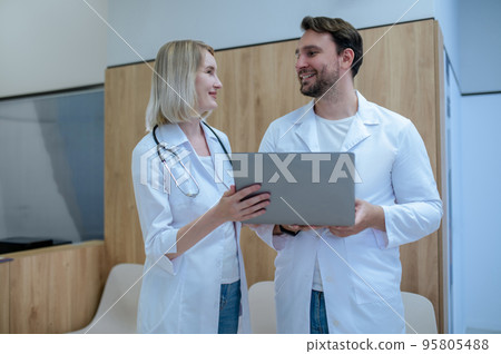 Cheerful doctor and his female colleague communicating in reception area Cheerful doctor and his female colleague communicating in reception area 95805488