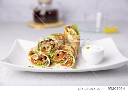 Pancakes with salmon (trout), sour cream, greenstuff and tea. Thin, not sweet blinchiki stuffed with red fish. Traditional Russian and Ukrainian dish. Feast of Maslenitsa. Selective focus, close-up. Pancakes with salmon (trout), sour cream, greenstuff and tea. Thin, not sweet blinchiki stuffed with red fish. Traditional Russian and Ukrainian dish. Feast of Maslenitsa. Selective focus, close-up. 95805934