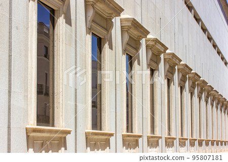 Classic old European architecture. Detail of an old beige building with many windows with beautiful frames, stucco. Spanish architecture in sunny day. Construction, preservation of buildings, houses. 95807181