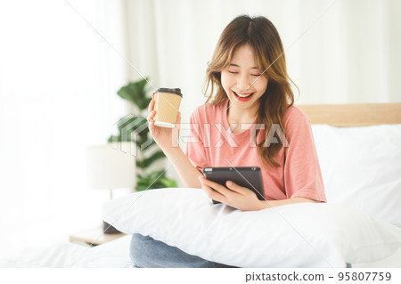 Woman using digital tablet for social message and mental health or shopping online at bedroom 95807759