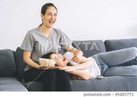 Two young asian woman couple living together on sofa at home or apartment 95807771