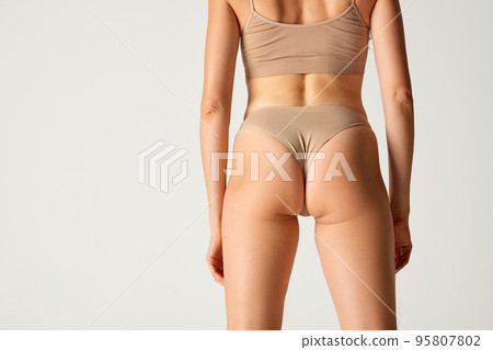 Cropped image of slim female body, back, waist and bttocks in underwear over grey background. Anti-cellulite treatment 95807802