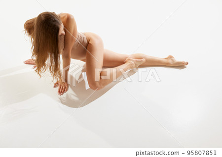 Portrait of beautiful woman posing in beige bodysuit over white studio background. Femininity and sexuality 95807851