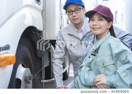 Male and female drivers inspecting truck tires Male and female drivers inspecting truck tires 95809064