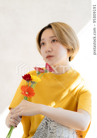 Portrait of young woman holding gerbera Portrait of young woman holding gerbera 95809191