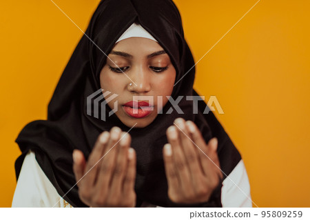 African muslim woman wearing hijab and traditional muslim clothes posing in front of yellow background African muslim woman wearing hijab and traditional muslim clothes posing in front of yellow background 95809259