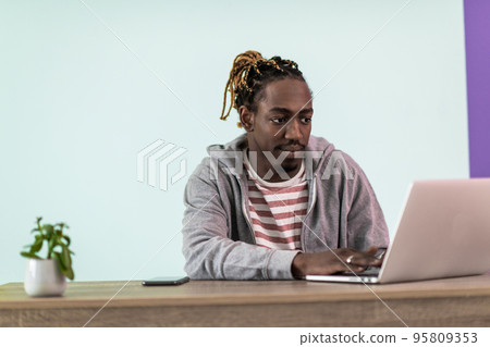 Smiling young african man freelancer using laptop studying online working from home Smiling young african man freelancer using laptop studying online working from home 95809353