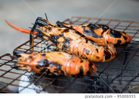 Grilled big shrimp that's being cooked on charcoal grill Grilled big shrimp that's being cooked on charcoal grill 95809355