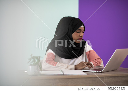 afro girl wearing a hijab is disappointed and sad sitting in her home office and using a laptop afro girl wearing a hijab is disappointed and sad sitting in her home office and using a laptop 95809385