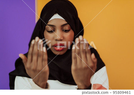 African muslim woman wearing hijab and traditional muslim clothes posing in front of yellow background African muslim woman wearing hijab and traditional muslim clothes posing in front of yellow background 95809461