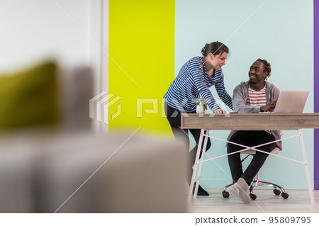Afro man and woman discussing together while using laptop in modern office 95809795