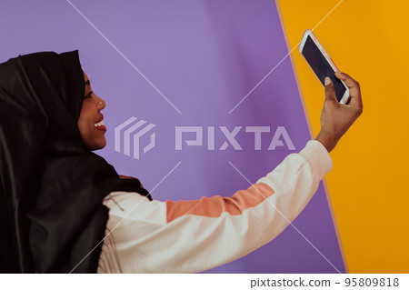 Afro woman using a smartphone in front of a pink background 95809818