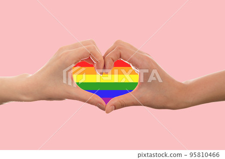 LGBT. Two females hands, shows the rainbow heart sign with their fingers. Copy space. Pink background. The concept of the LGBT movement and gay day 95810466