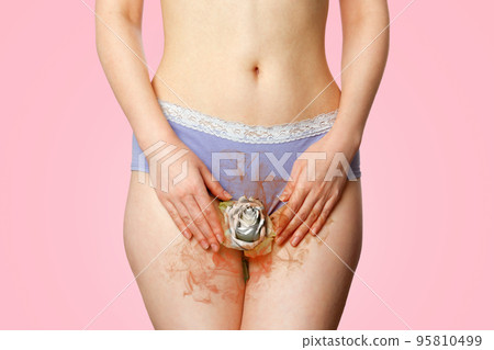 A woman in underwear holds a white rosebud between her legs, at the level of her intimate organs, exuding a stench. Close up. Pink background. Concept of women's gynecological problems and menopause 95810499