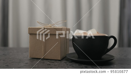 gift box near black cup with hot chocolate on concrete countertop gift box near black cup with hot chocolate on concrete countertop 95810877