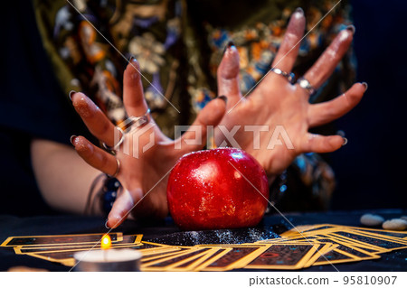 A fortune teller conjures a red apple lying on the Tarot cards. Close up. The concept of divination, astrology and esotericism A fortune teller conjures a red apple lying on the Tarot cards. Close up. The concept of divination, astrology and esotericism 95810907