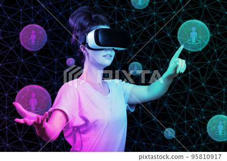 Metaverse. Portrait of woman in VR glasses point a digital sphere with person symbol. Black background. Concept of communication, virtual reality and cyberspace Metaverse. Portrait of woman in VR glasses point a digital sphere with person symbol. Black background. Concept of communication, virtual reality and cyberspace 95810917