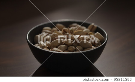 roasted pistachios in black bowl on walnut table 95811593