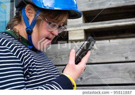 40 yo white woman with the Down Syndrome having a video call with her family on the phone 95811887