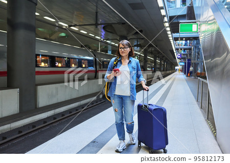 Woman with suitcase backpack on station platform Woman with suitcase backpack on station platform 95812173