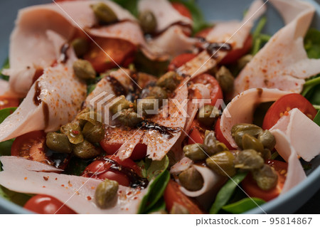 Salad with prosciutto cotto, cherry tomatoes and spinach in blue bowl closeup 95814867