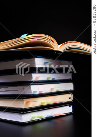 Close-up of a stack of office notepads with colorful sticky page markers with one open notepad on top Close-up of a stack of office notepads with colorful sticky page markers with one open notepad on top 95815290