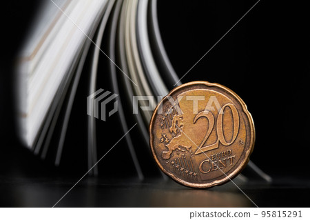 Close-up of a twenty cent euro coin on the background of magazine pages Close-up of a twenty cent euro coin on the background of magazine pages 95815291