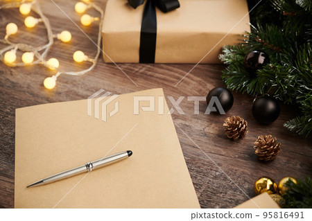 Blank sheet and pen on table with Christmas tree and wrapped present 95816491