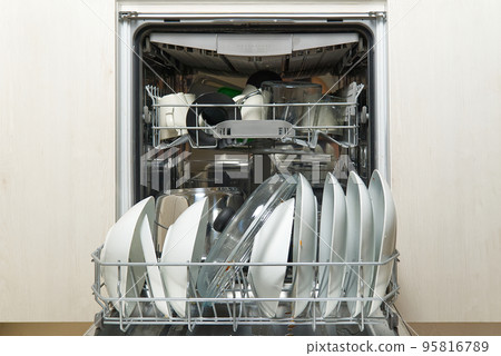 Dirty dish in open integrated dishwasher. Open dishwasher with dirty dishes inside before washing. full loaded dishwasher ready for washing. 95816789