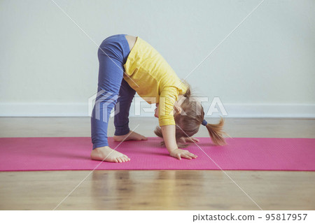 Charming baby doing yoga at home. Place for text 95817957
