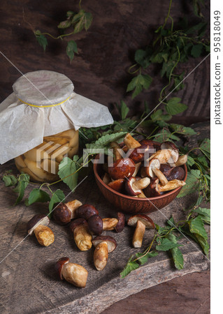 Pile of Imleria Badia or Boletus badius mushrooms commonly known as the bay bolete with canned mushroom in glass jar on vintage wooden background.. Pile of Imleria Badia or Boletus badius mushrooms commonly known as the bay bolete with canned mushroom in glass jar on vintage wooden background.. 95818049